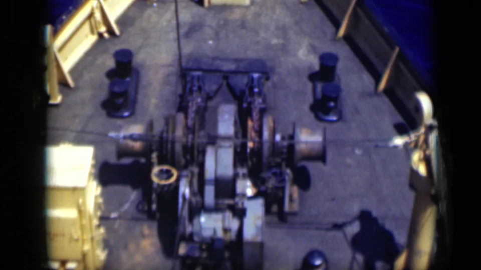 1946 Egypt 8mm frame showing the fishing boat's deck machinery, cable or net spools, bow railings and surrounding blue water from a high onboard angle.