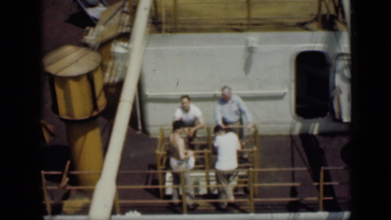 Four men appear on a Cairo boat deck in 1946, framed by yellow railings, a white cabin wall, and a dark doorway.