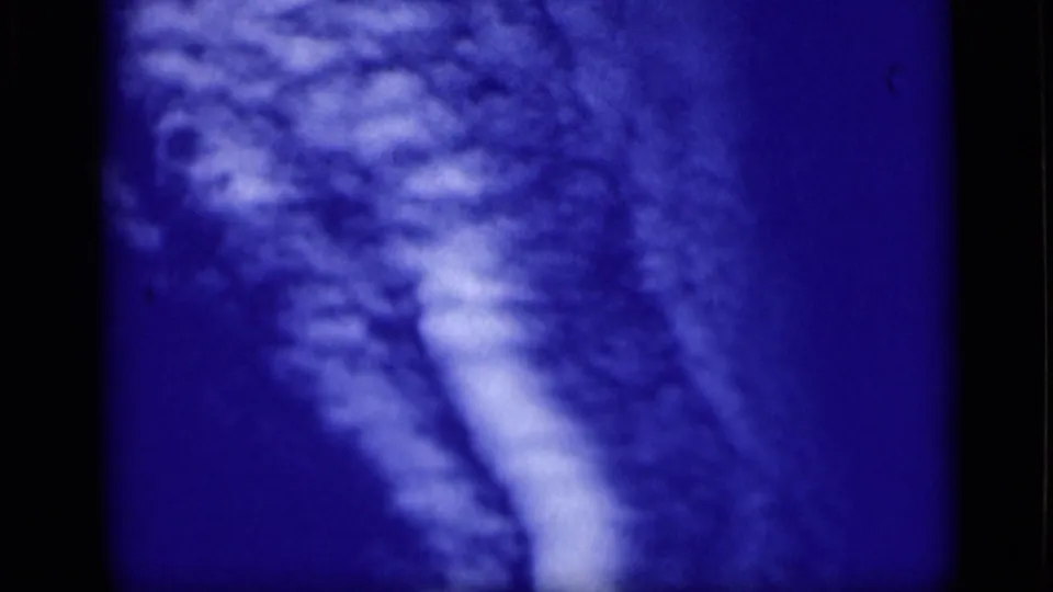 A deep blue 8mm frame shows pale textured cloud forms, soft focus, and strong color shift.