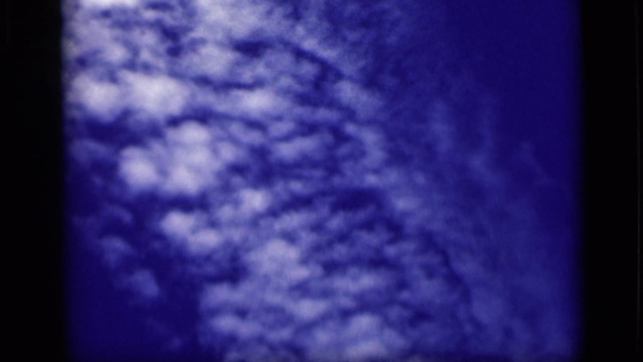 1946 Cairo 8mm frame showing textured white clouds against a deep blue sky, with dark film-edge borders visible.