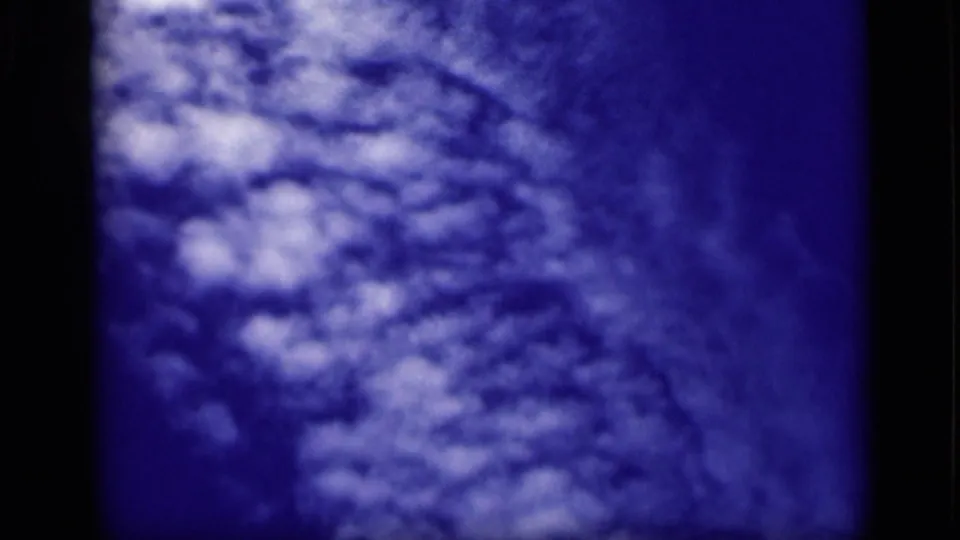 1946 Cairo 8mm frame showing textured white clouds against a deep blue sky, with dark film-edge borders visible.