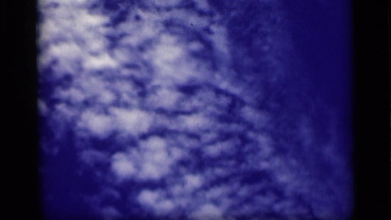 White cloud mass against blue sky with soft focus and film grain.