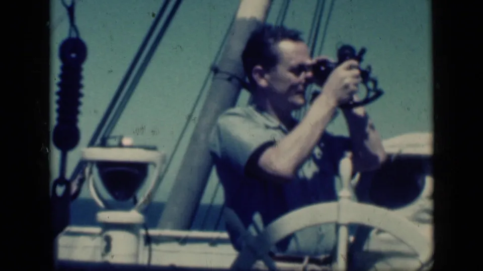 Adult man using a sextant on a boat deck, with wheel, railing, and rigging visible in 1940s Cairo travel footage metadata.