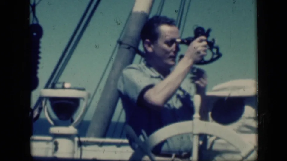 In 1946 Cairo home-movie footage, a man uses a sextant aboard a vessel with a white wheel, mast, and rigging visible.