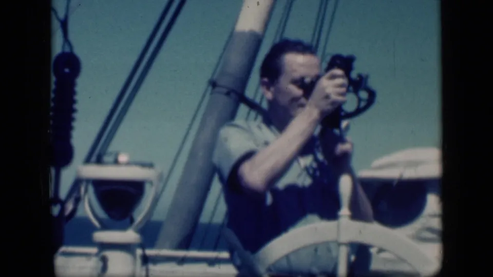 In Cairo, Egypt in 1946, a man aboard a sailboat raises a small cine camera near a white wheel, mast, and rigging.