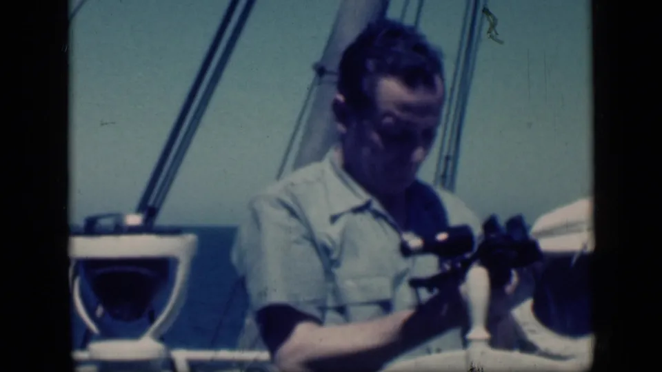 In 1946 Egypt travel footage, an adult man on a boat looks down while holding binoculars near rigging and sea.