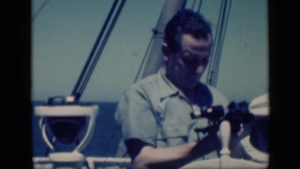 A man aboard a boat in metadata-supported 1946 Egypt adjusts binoculars, with rigging, sea, and film edge visible.