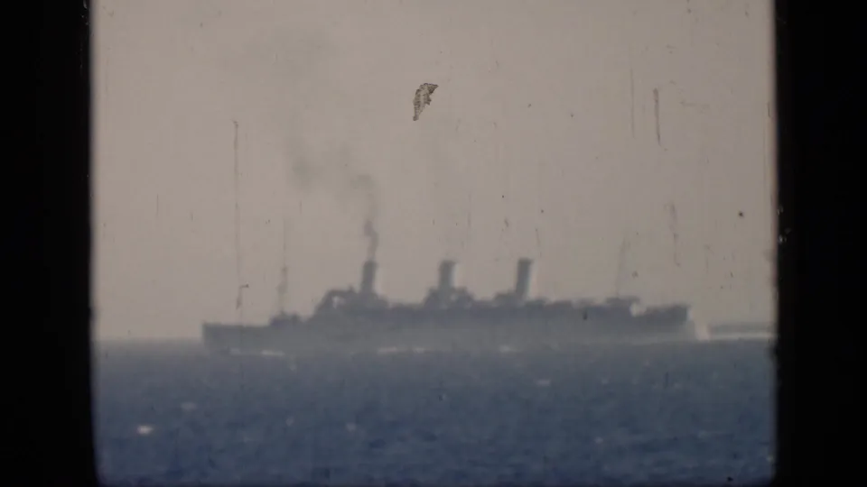 Distant 1946 maritime home-movie view of a large steamship moving across the sea beneath a pale, hazy sky.
