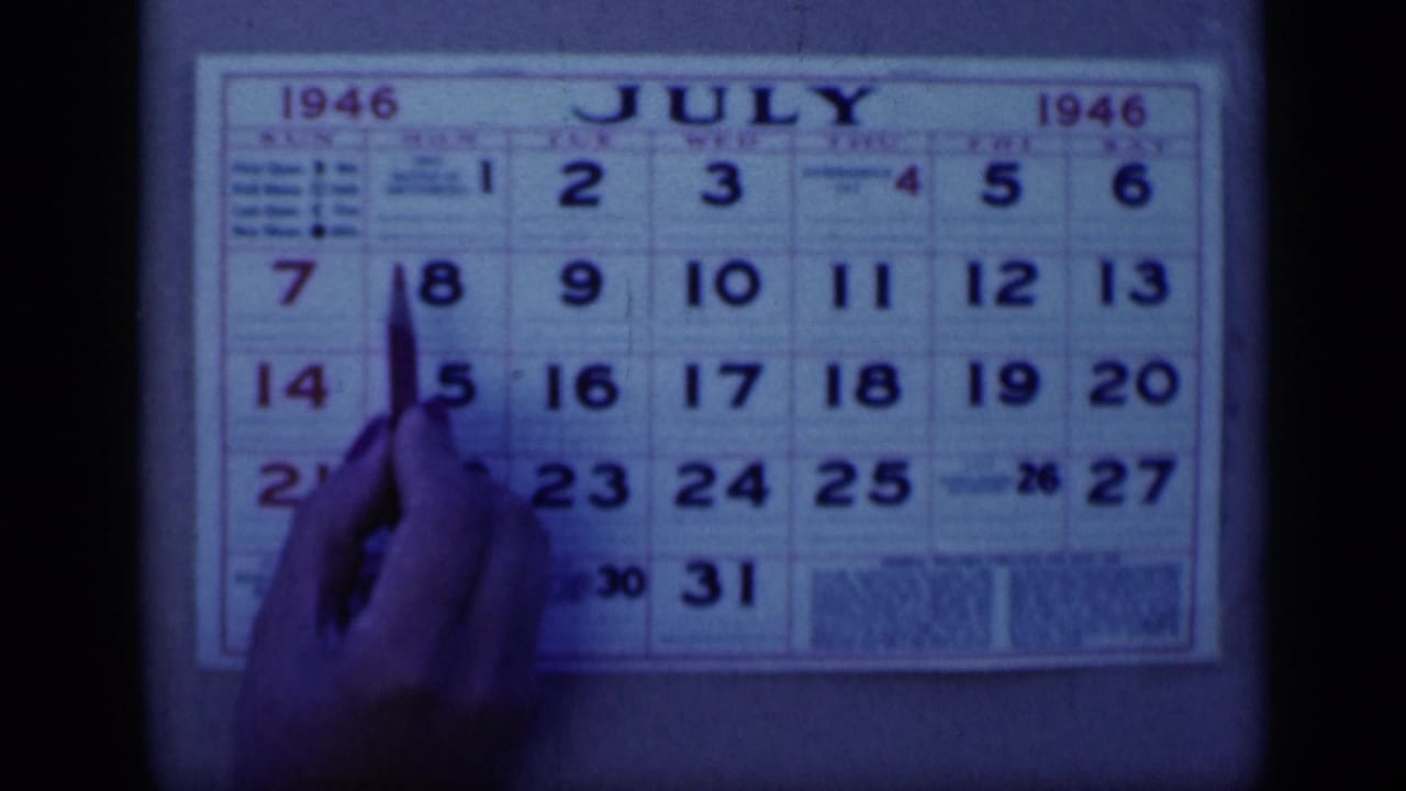 In 1946 Cairo home-movie footage, a hand uses a pen near July 8 on a July 1946 wall calendar.