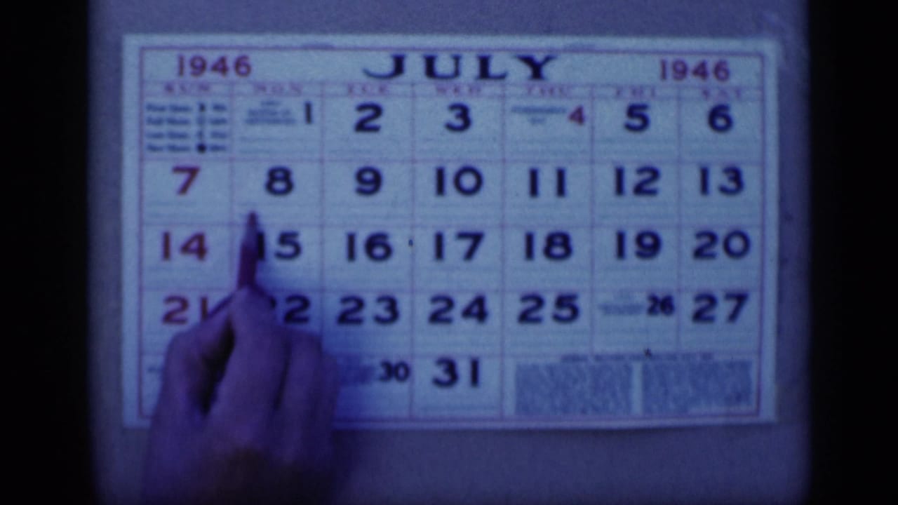Pen and hand held over the July 8 square on a 1946 calendar.
