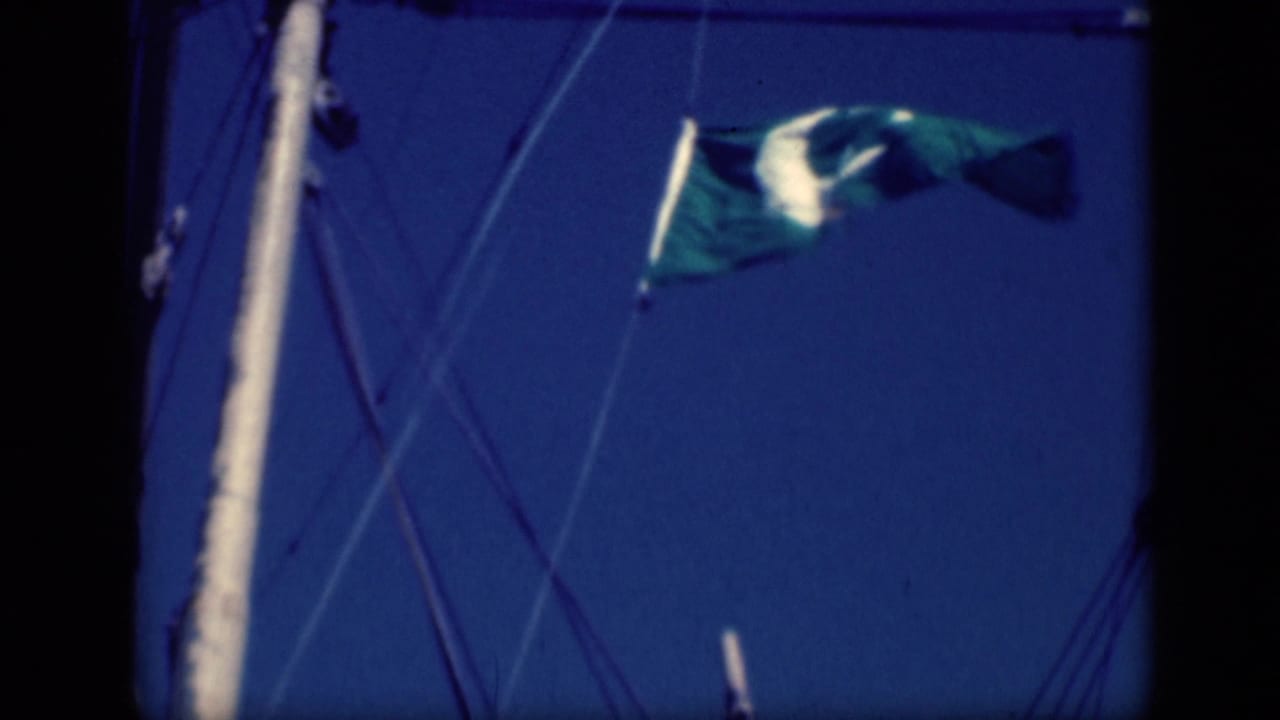 1946 Cairo frame of a green crescent-and-star flag fluttering high on sailboat rigging against a deep blue sky.