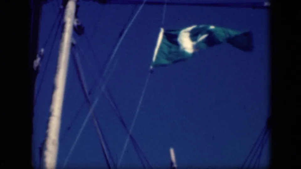 1946 Cairo frame of a green crescent-and-star flag fluttering high on sailboat rigging against a deep blue sky.