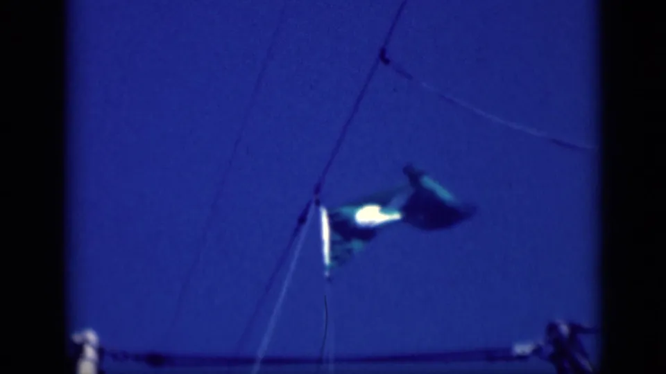 1946 8mm frame with the United States flag blurred by motion near rigging lines, set against a saturated blue sky.