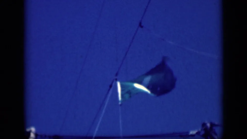 1946 8mm frame showing a close, soft-focused view of the shipboard flag and diagonal rigging against blue sky.