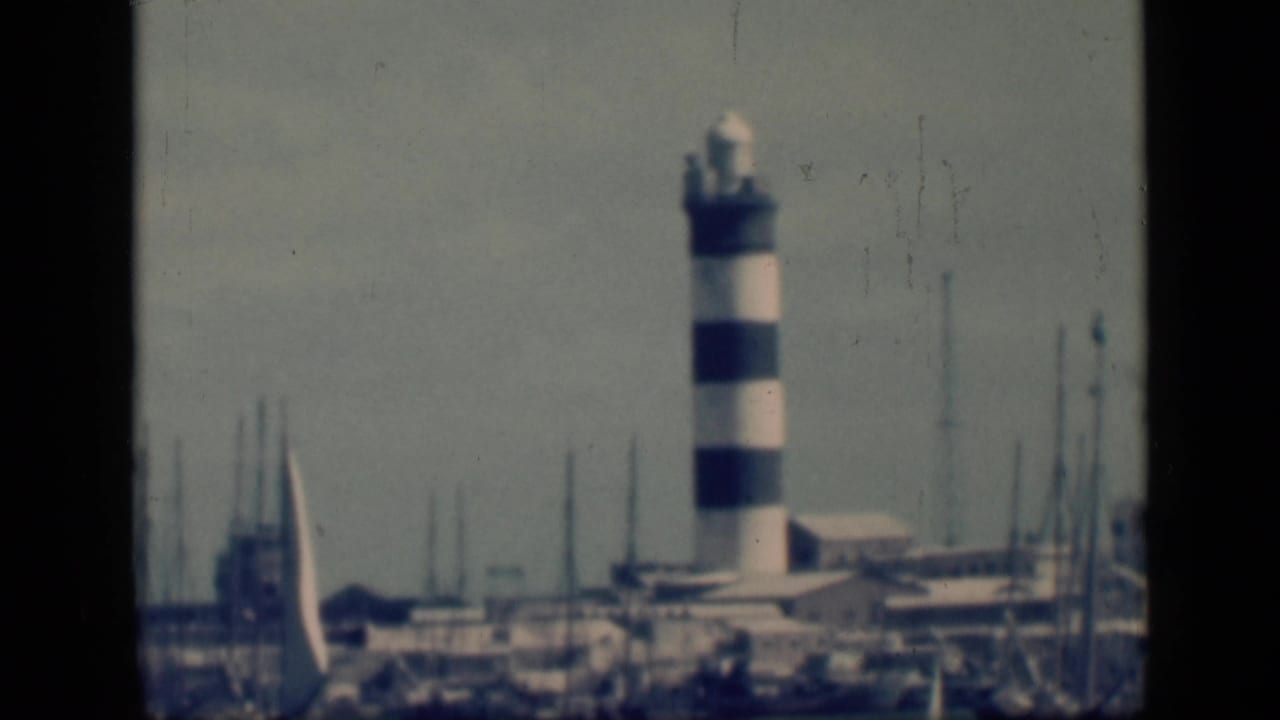 1946 Cairo, Egypt home-movie frame showing a black-and-white striped harbor light near boats and low waterfront structures.