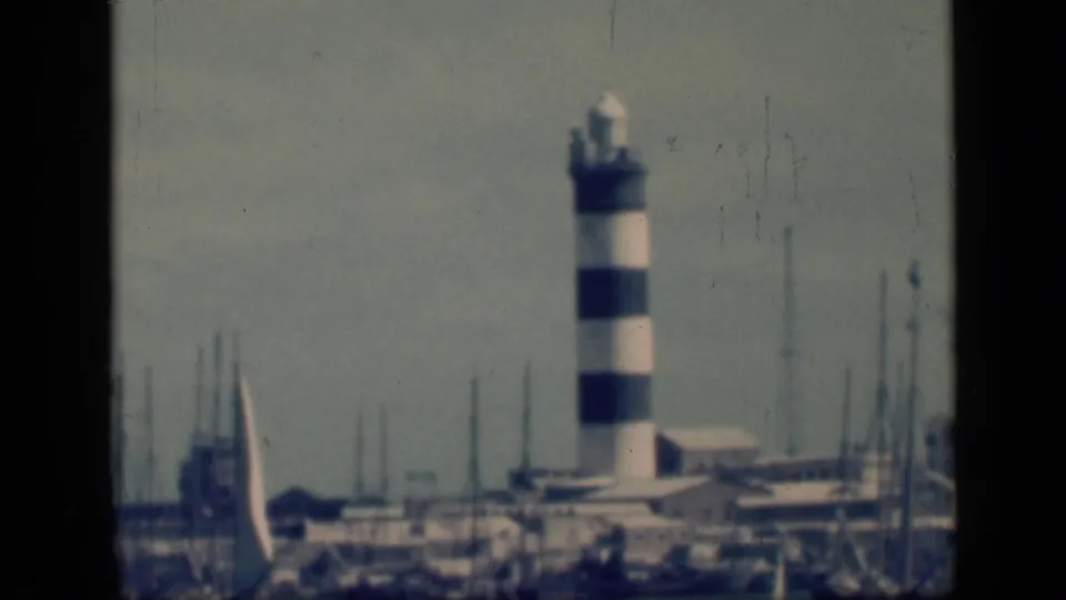 1946 Cairo, Egypt home-movie frame showing a black-and-white striped harbor light near boats and low waterfront structures.