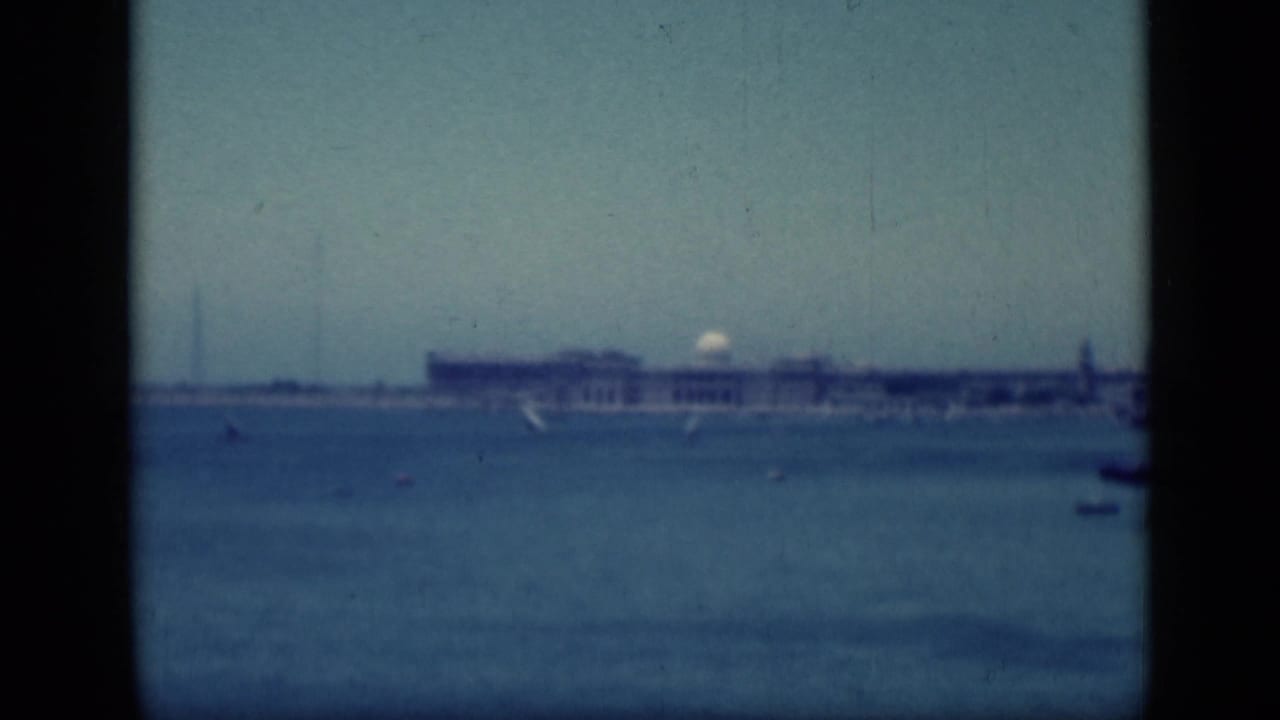 1946 home-movie view in Cairo, Egypt, showing a hazy waterfront building and small sailboats through dark window-like framing.