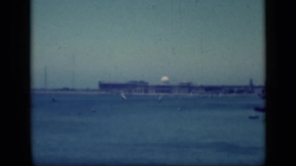 1946 home-movie view in Cairo, Egypt, showing a hazy waterfront building and small sailboats through dark window-like framing.