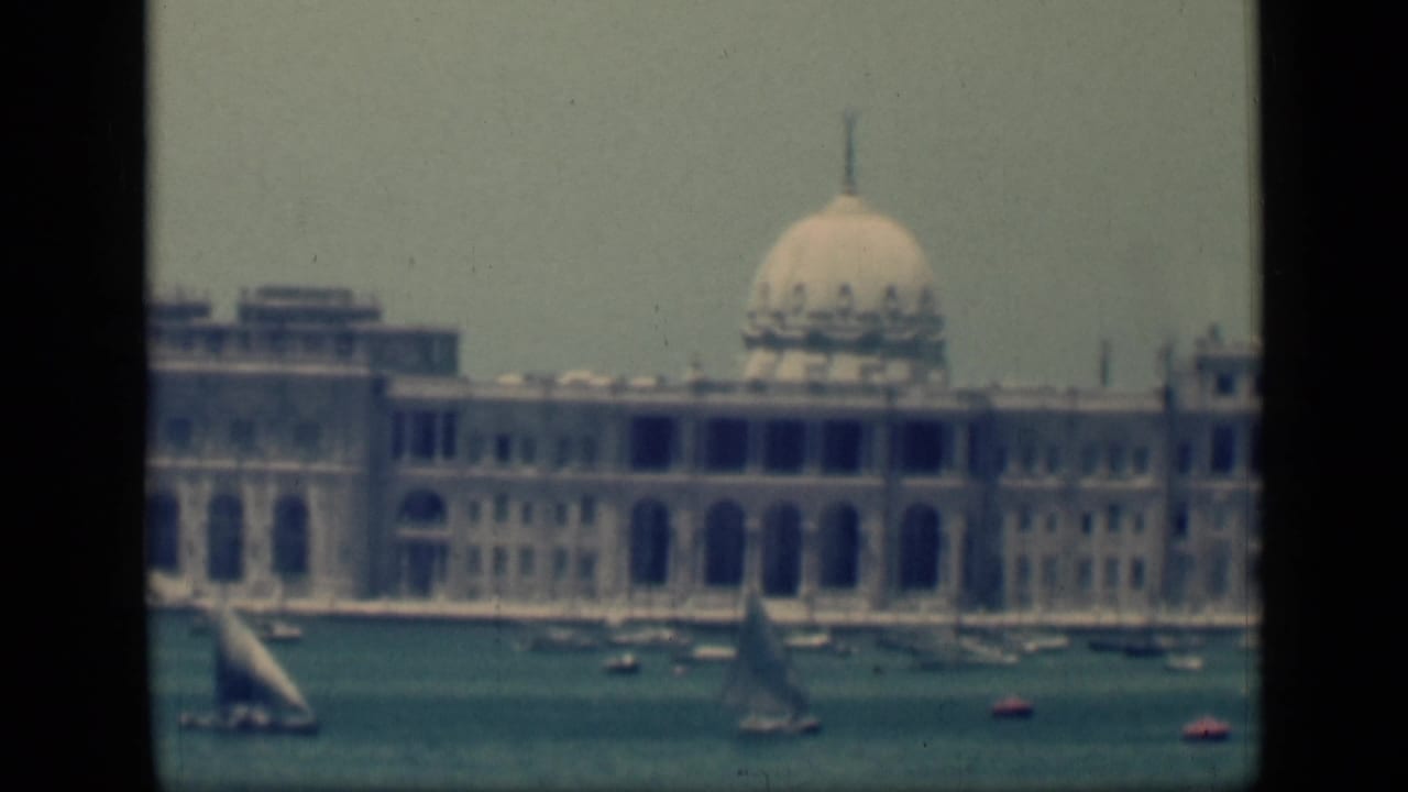 1946 Egypt 8mm frame showing a domed waterfront building beyond sailboats and small boats on the harbor.