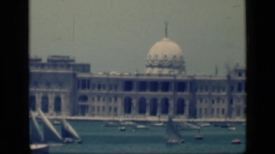 1946 Egypt 8mm view of the domed waterfront building with several small sailboats crossing the water.