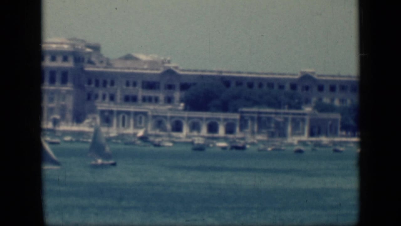 1946 Cairo harbor scene showing a sailboat and moored boats below a long waterfront building with pale arches.