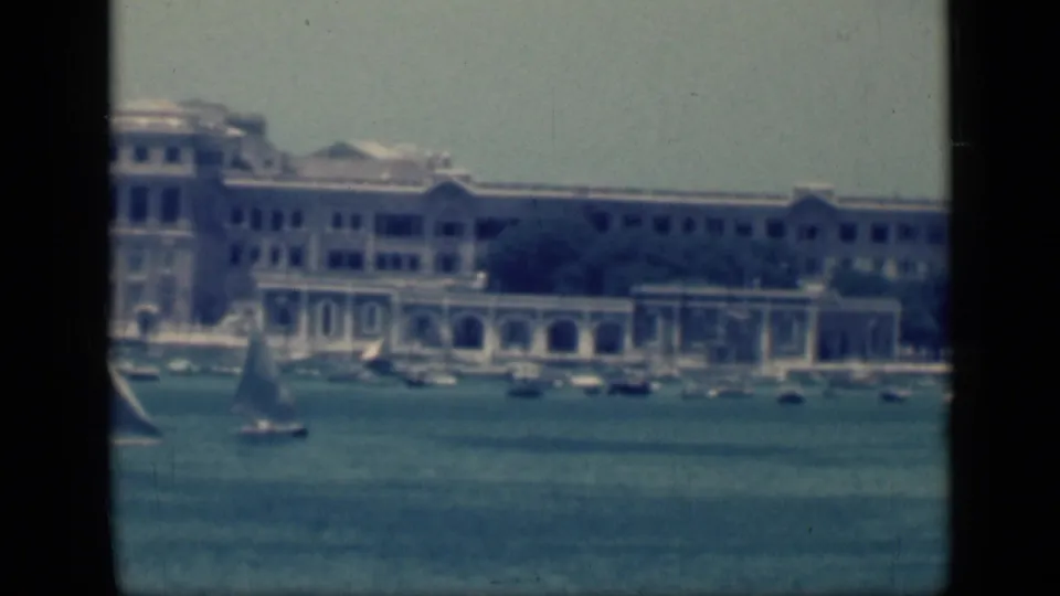 1946 Cairo harbor scene showing a sailboat and moored boats below a long waterfront building with pale arches.