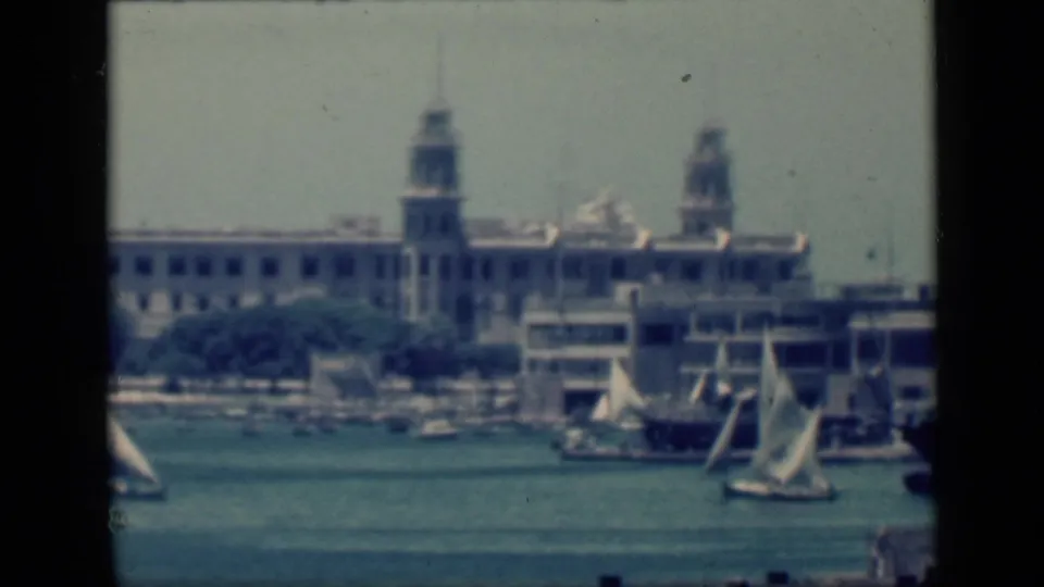 1946 Cairo, Egypt home-movie frame with white-sailed boats on the water and a large urban waterfront behind them.