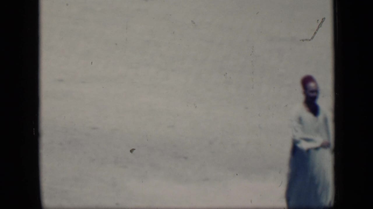 In 1946 Cairo footage, a man in a white robe and red fez-style hat appears near the edge of a sunlit open area.