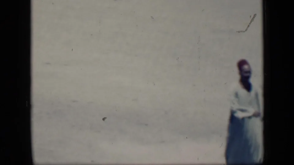 In 1946 Cairo footage, a man in a white robe and red fez-style hat appears near the edge of a sunlit open area.