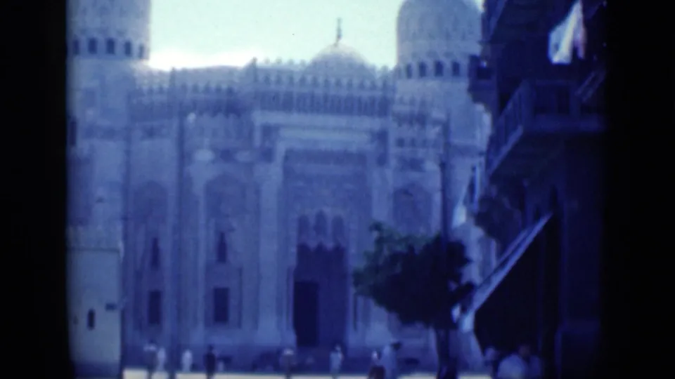 Soft blue-shifted 8mm frame from Cairo in 1946, showing pedestrians near a large domed mosque facade.