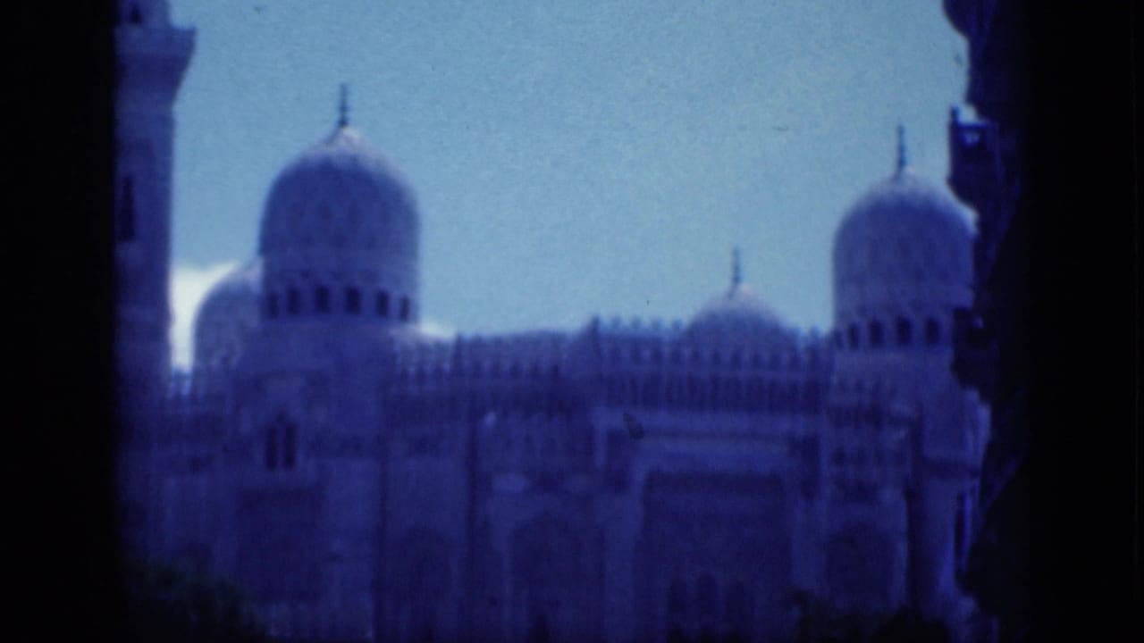 1946 Cairo 8mm frame showing mosque domes and a tall facade area viewed from a shaded opening with a blue color cast.