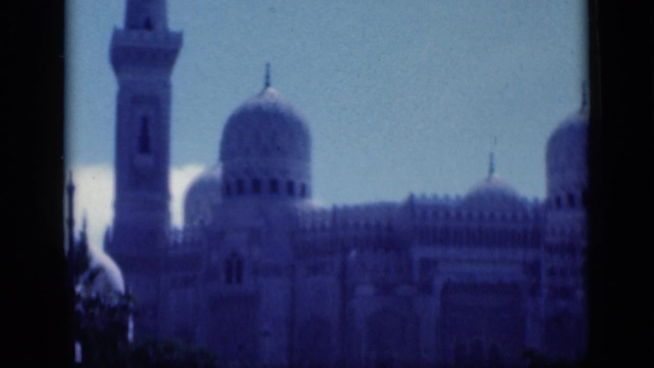 Tall minaret and mosque domes partly obscured by dark vertical framing.
