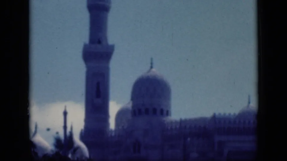 1946 Cairo 8mm frame with a minaret, prominent dome, smaller domes, and dark foreground framing around the mosque.