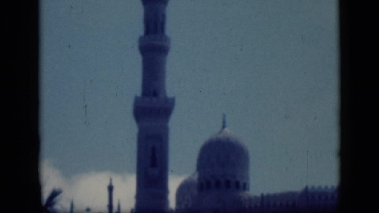 Minaret and mosque dome framed by dark vertical edges.