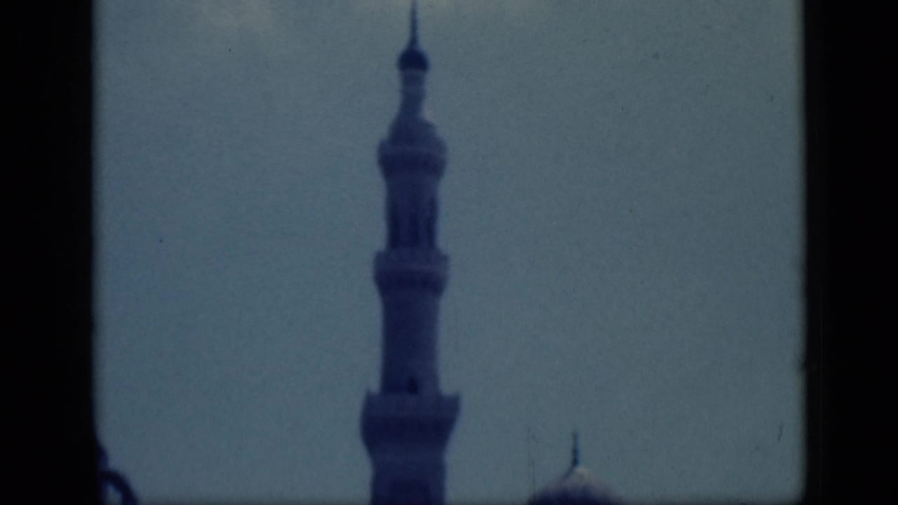 1946 Cairo home-movie frame showing a mosque minaret against pale sky, with dark borders and soft 8mm focus.