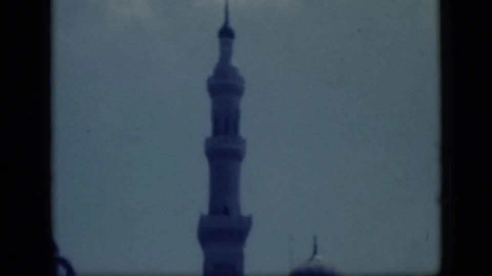 1946 Cairo home-movie frame showing a mosque minaret against pale sky, with dark borders and soft 8mm focus.