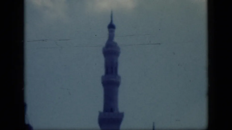 1946 Cairo 8mm frame with a centered mosque minaret, pale sky, soft blue tint, and visible film scratches.