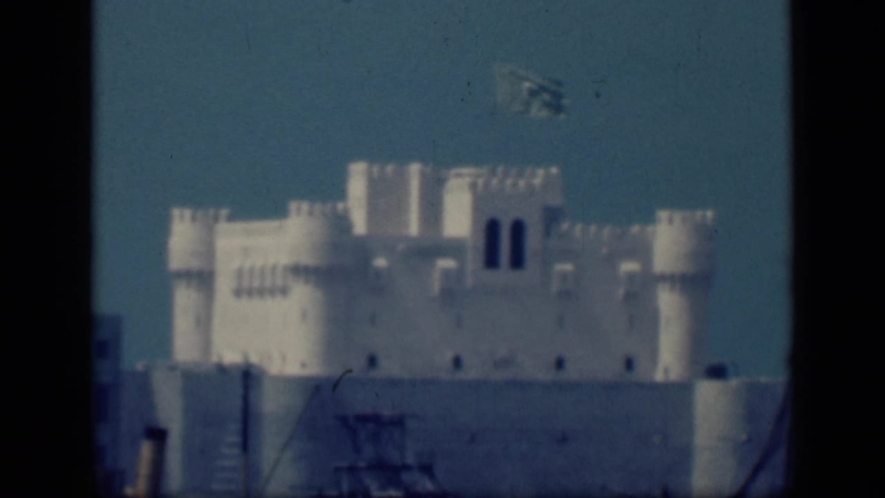 1946 Cairo home-movie frame showing a distant white castle-like structure with towers and a waving blue crescent-and-star flag.