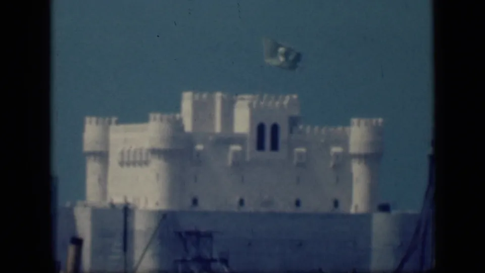 Soft-focused 1946 Cairo 8mm frame showing the white crenellated structure, roofline towers, and flag above the building.
