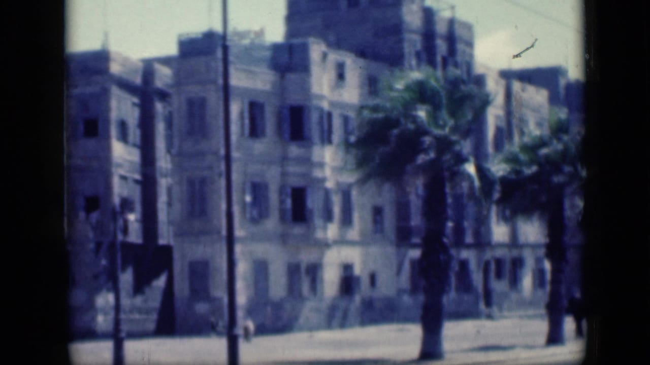 1946 Cairo street view with windblown palms, shuttered building facades, a roadway, and small pedestrians in the distance.