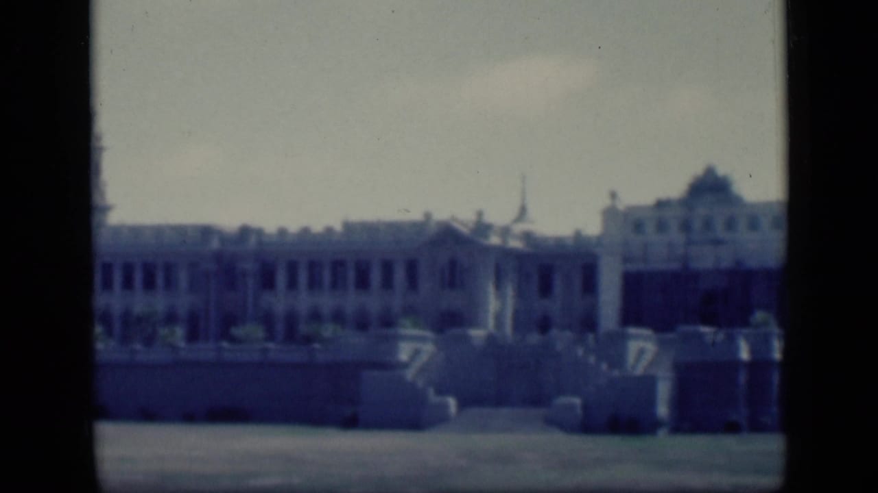 Long pale facade with raised wall, steps, and a central tower-like roofline.