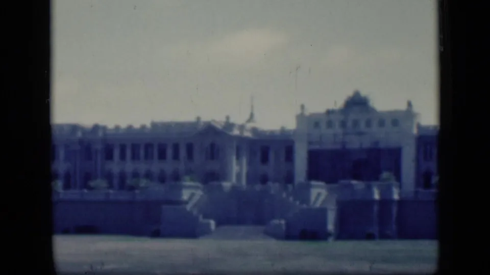 1946 Cairo home-movie still showing a palace-like building across an open paved area, framed by faded 8mm color.