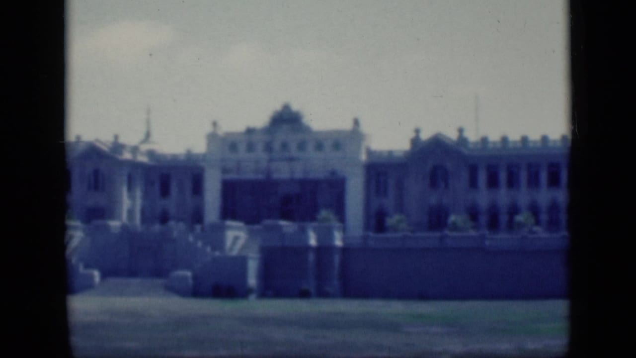 1946 Cairo frame of a large symmetrical building exterior, with a prominent central section, arched details, perimeter walls, and soft blue color cast.