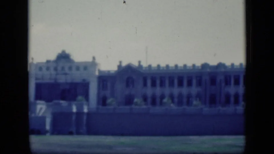 1946 Cairo frame showing a long section of a grand building, with repeated upper windows, arched architectural details, open ground, and dark scan borders.