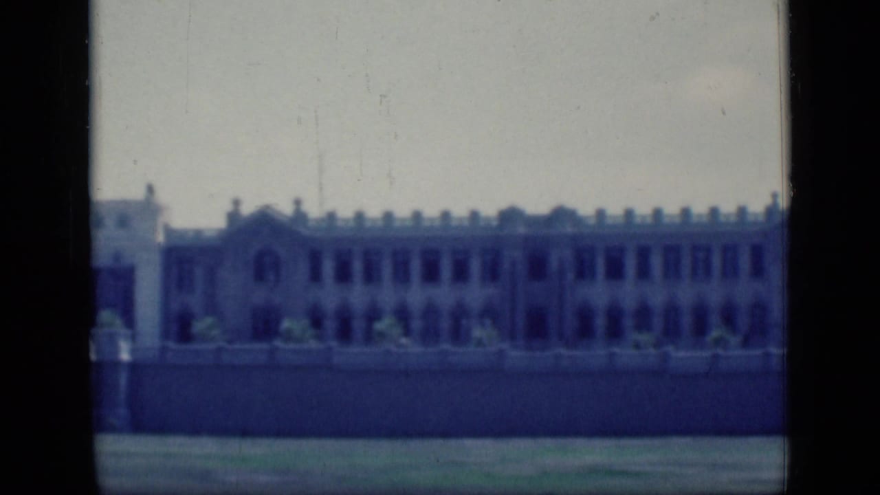 Long pale building facade seen through dark vertical film borders.