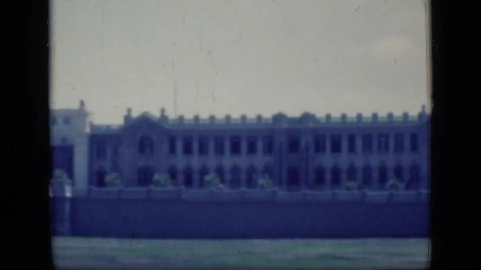 1946 Cairo 8mm frame with a long white or pale facade, repeated windows, low wall and open foreground.