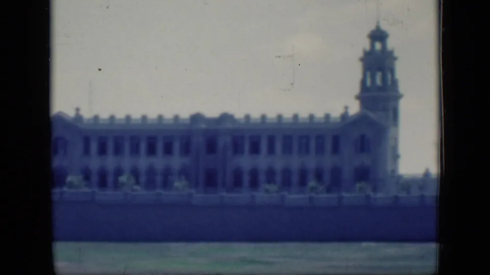 1946 Cairo 8mm frame ending on the long pale building with tower, boundary wall and grassy foreground.
