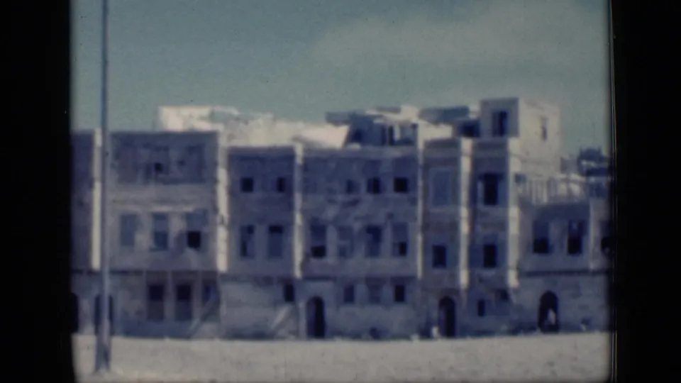 1946 Cairo footage showing a row of pale urban buildings with many dark window openings and a foreground pole.