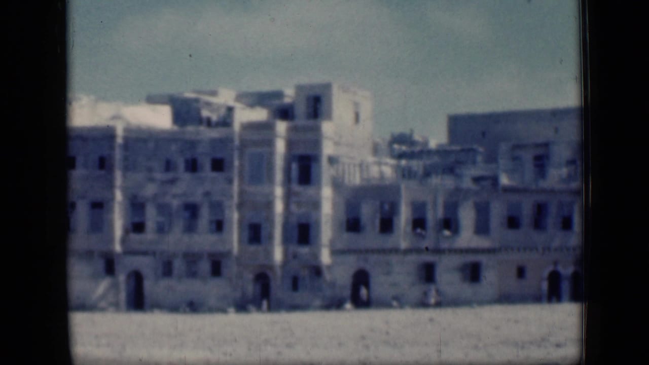 1946 Cairo frame with a distant white building ensemble, arched entrances, window rows, and open ground in front.