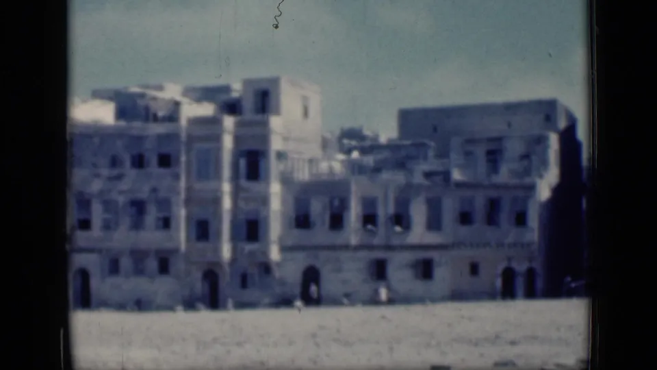 Soft 8mm frame from Cairo in 1946 showing pale architectural facades and arched doorways beyond a broad open foreground.